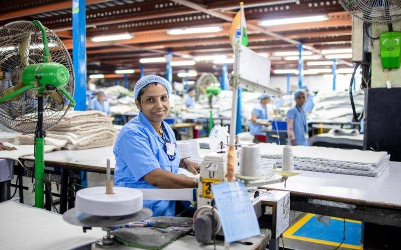 Smiling worker at a textile factory sewing station